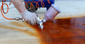 A man expertly sprays a wood floor
